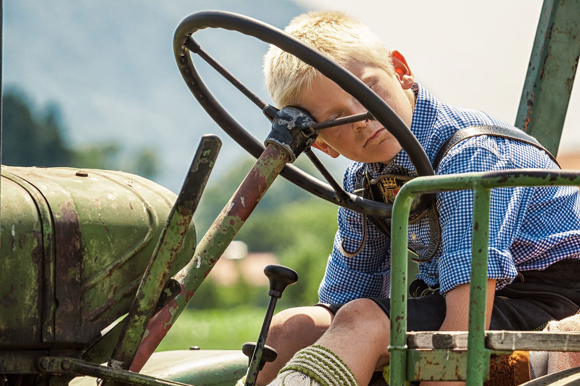 Kind liegt auf dem Traktor am Bauernhof und schläft