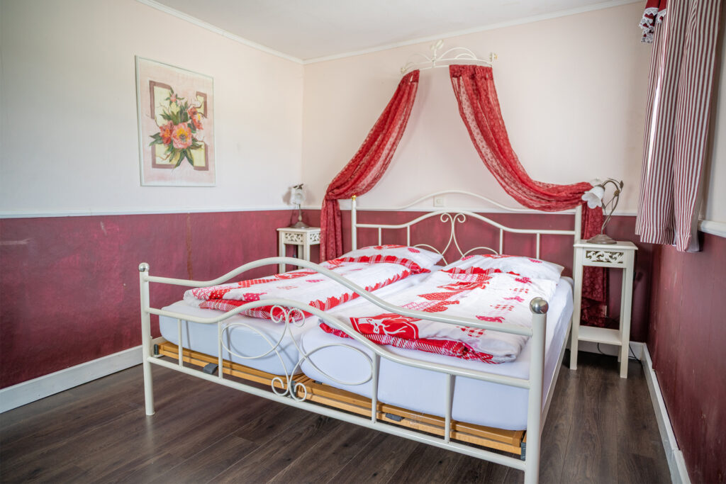 Schlafzimmer der Ferienwohnung Rustica mit Baldachin und rot-weißer Bettwäsche