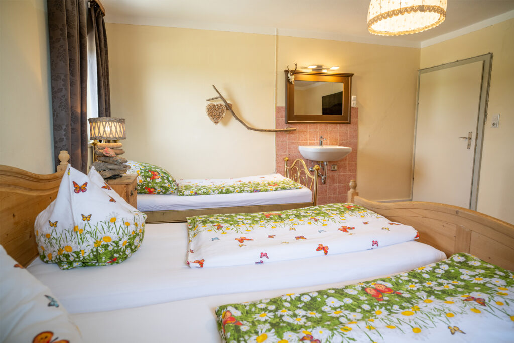 Blick ins das Schlafzimmer der Ferienwohnung Seeblick mit Betten und an der Wand ein Waschbecken
