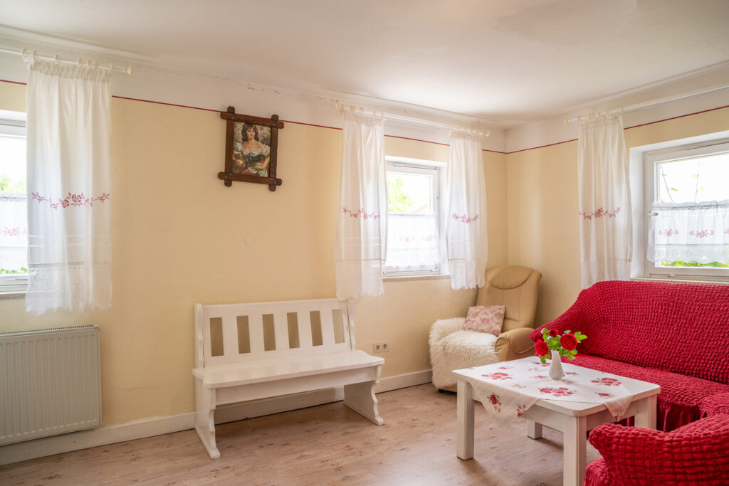 Wohnbereich mit Sofa, Holzbank, Sessel und 3 Fenster