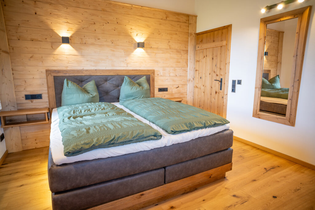 Doppelbett, Spiegel und gemütliches Landhaus-Style in der Ferienwohnung Alpenblick