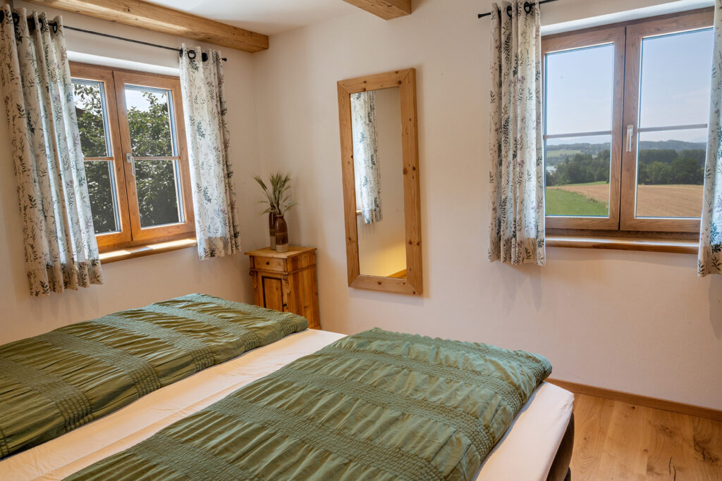 Schlafzimmer mit Blick in die Waginger See Region, Doppelbett, 2 Fenster, Spiegel und Holzschränkchen